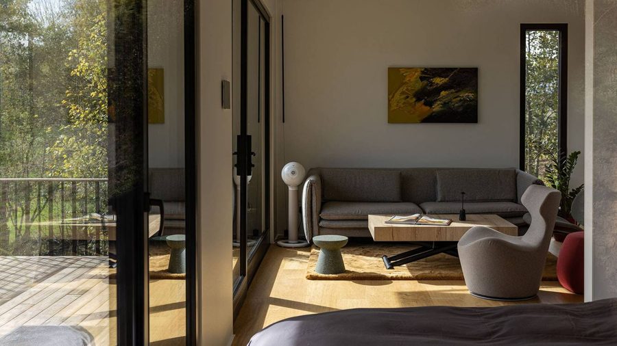 Blick durch die geöffnete Verglasung in den Schlafbereich des TR01 mit Bett und Kunst an der Wand