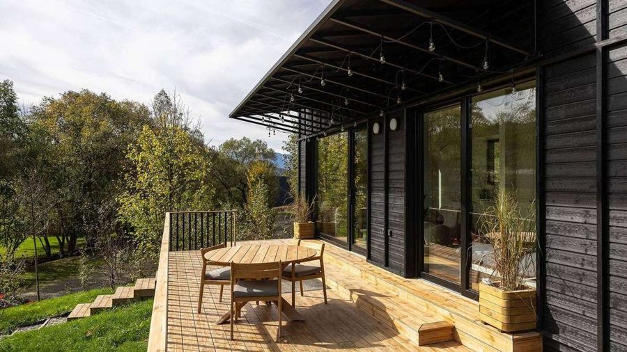 Terrasse des TR01 mit rundem Esstisch und Stühlen, Blick über die Wiesenlandschaft