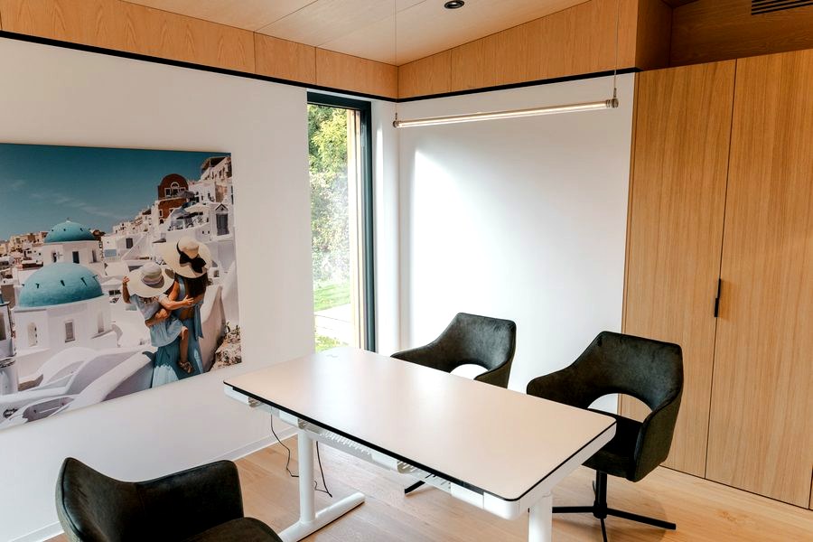 Zweites Zimmer im Musterhaus TR3M als Arbeitszimmer: höhenverstellbarer Schreibtisch, Eichenschrank, Fenster zum Garten