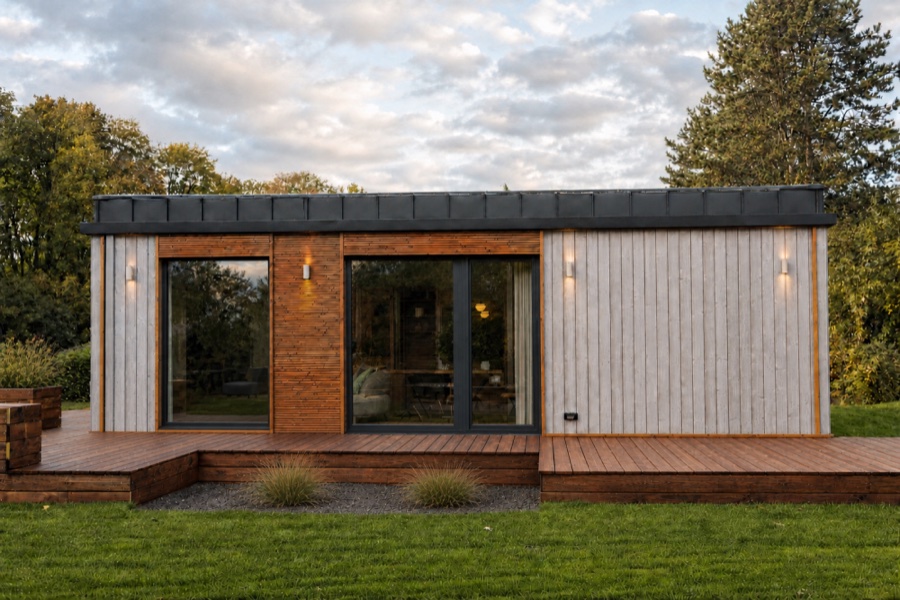 Gartenfassade des TR3M mit grauer und warmer Holzverkleidung, großer Verglasung und Terrasse